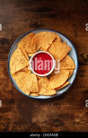 Nacho chips with a tomato salsa, served on a plate, shot from above on a rustic wooden background Stock Photo