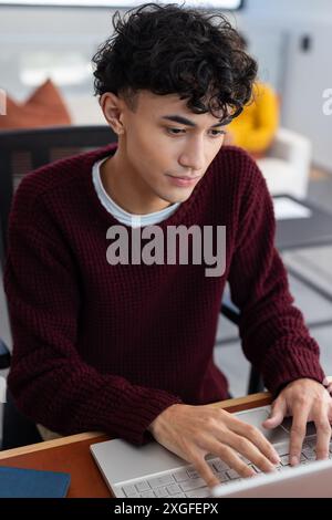 Typing on laptop, young man working from home in cozy living room Stock Photo