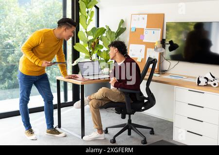 Discussing work, two men collaborating with laptop in modern home office Stock Photo