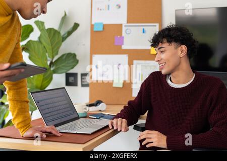 Working from home, smiling man using laptop and discussing with partner Stock Photo