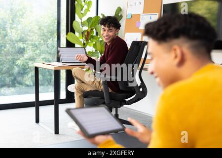 Using tablets and laptops, two men working and smiling in home office Stock Photo
