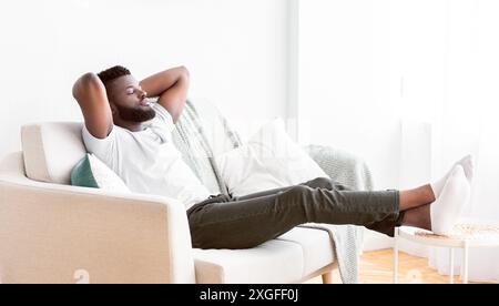 Relaxed Man Resting On White Couch In A Living Room Stock Photo