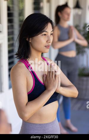 Practicing yoga, women friends in sportswear doing prayer pose at home Stock Photo