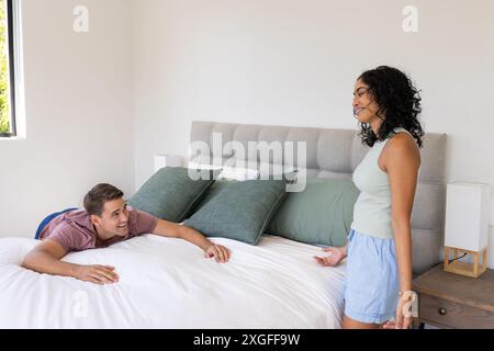 Young couple relaxing and talking on bed in modern bedroom setting Stock Photo