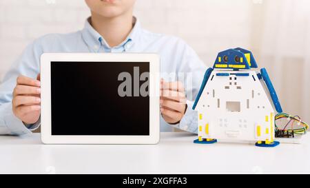 Boy Holding a Tablet in Front of a Robot Toy Stock Photo