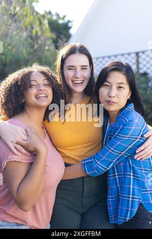 Hugging and smiling, three diverse women friends outdoors enjoying friendship and togetherness Stock Photo