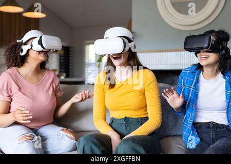 Using VR headsets, three women friends enjoying virtual reality experience together Stock Photo