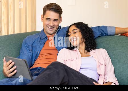 Relaxing on couch, young couple smiling and watching tablet together Stock Photo
