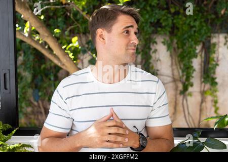Young man in striped shirt standing and looking to side, outdoors Stock Photo
