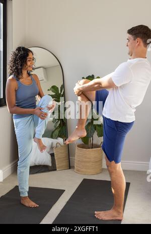 Practicing yoga, young couple balancing on one leg on yoga mats indoors Stock Photo