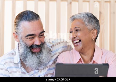 Smiling senior couple using tablet and enjoying time together indoors Stock Photo