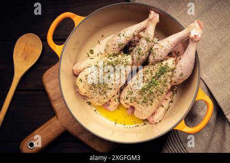 Uncooked Spicy chickens in cast iron cooking pot on wooden table. Spanish traditional recipe. Top view Stock Photo