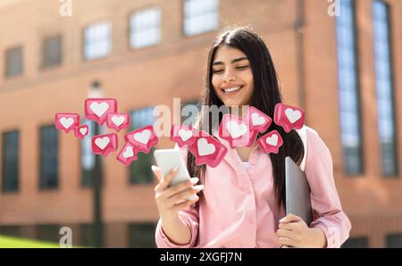Young Woman Using Smartphone With Heart Icons Over University Building Stock Photo