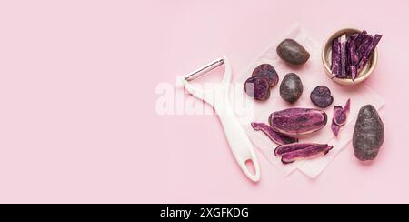Raw purple potatoes and peeler on pink background with space for text Stock Photo