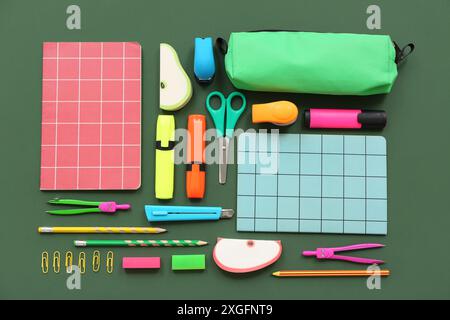 Composition with notebooks and different stationery on green background Stock Photo