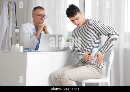 Ill young man putting hot water bottle to his kidney at urologist's office Stock Photo