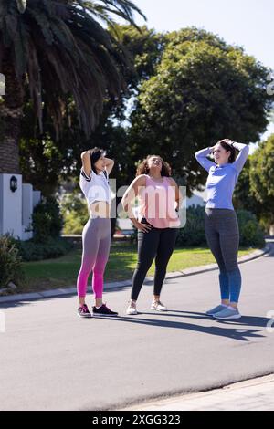 Exercising outdoors, three women friends stretching and relaxing after workout session Stock Photo