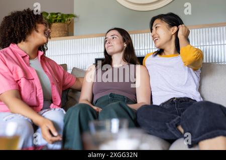 Sitting on couch, three women friends talking and laughing together at home Stock Photo