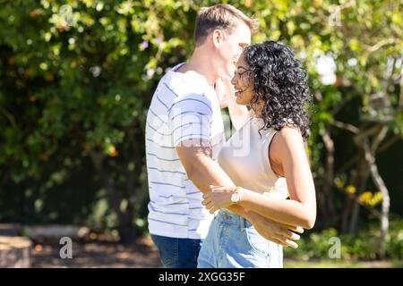 Young couple dancing together outdoors, enjoying sunny day in park Stock Photo