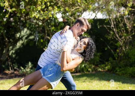Young couple dancing and laughing together in sunny outdoor garden Stock Photo