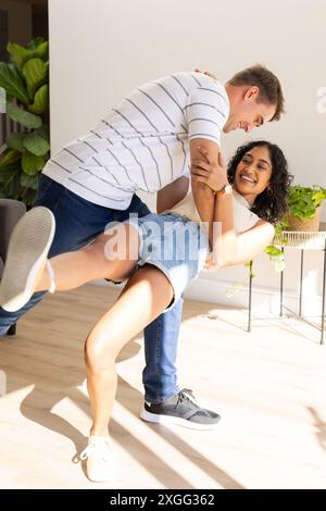 Dancing together, young couple enjoying playful moment in bright living room Stock Photo