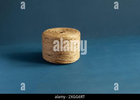 An insolated spool of natural fiber twine  natural color jute twine set against a striking hand-painted blue background with copy space focus on the t Stock Photo