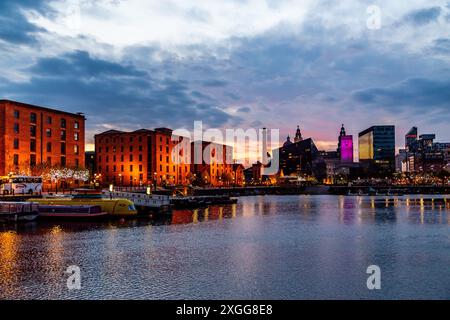 Twilight view of illuminated historic brick warehouses at Royal Albert Dock and the Liverpool waterfront promenade at dusk, Merseyside, England Stock Photo