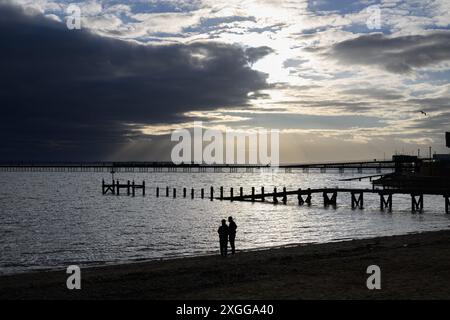 16th February 2024: Beach goers on Southend-on-Sea Beach silhouetted  against the late afternoon sun. Stock Photo