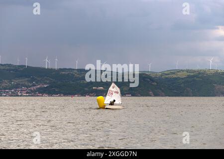 Golubac, Serbia, May 31, 2024: During the Optimist Class sailing regatta on the Danube River, a young sailor maneuvers past a buoy. Stock Photo