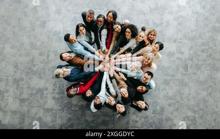 Top view of a diverse team of people joining hands in a collaborative and inclusive business environment, symbolizing unity and teamwork. Stock Photo