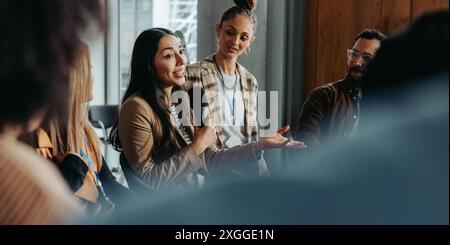 Woman talking and engaging in a debate with peers during a group meeting, sharing ideas and opinions. Stock Photo