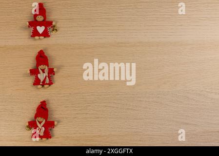 Three Christmas fairies in red woollen hats on a wooden table. Copy space Stock Photo