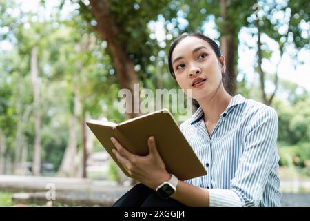 Young Digital Nomad Enjoying Outdoor Work Environment with Laptop and Notebook in a Park Setting Stock Photo