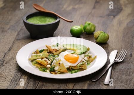 chilaquiles, Mexican breakfast. Totopos topped with salsa verde, fried egg, and avocado. Stock Photo