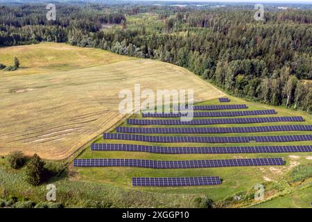Aerial view of solar panels arranged in rows across a lush green field ...