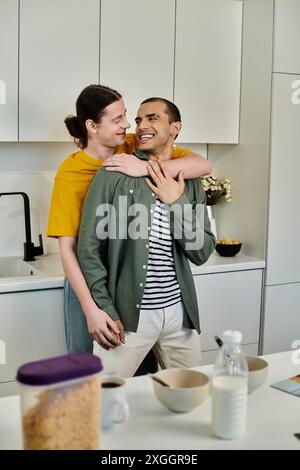 A young gay couple shares a lighthearted moment in their modern kitchen, embracing and laughing together. Stock Photo