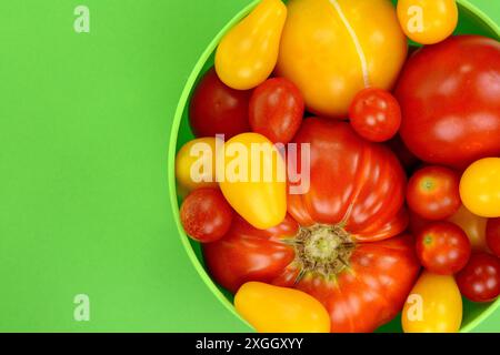 Different Kinds of Organic Tomatoes in a Bowl isolated on green background Stock Photo