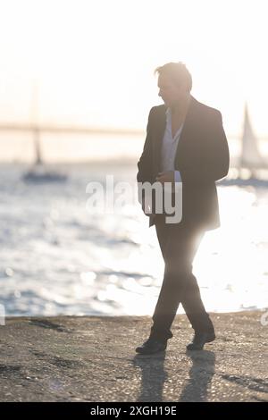 A man is walking on a beach near the water Stock Photo