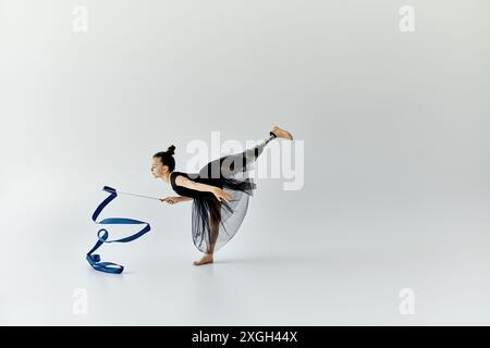 A young gymnast with a prosthetic leg performs a graceful routine with a ribbon. Stock Photo