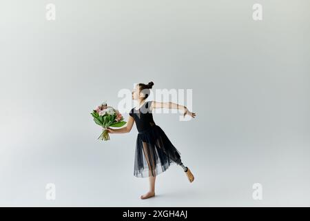 A young gymnast with a prosthetic leg performs a graceful pose while holding a bouquet of flowers. Stock Photo