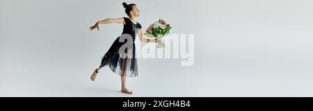 A young gymnast with a prosthetic leg performs a graceful pose while holding a bouquet of flowers. Stock Photo