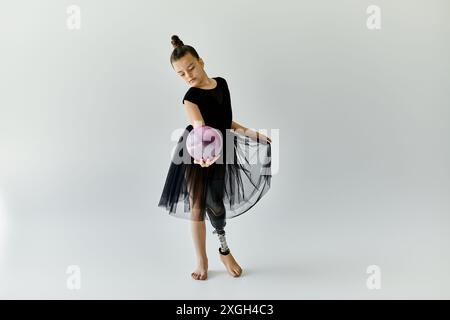 A young gymnast with a prosthetic leg performs a graceful routine with a purple ball. Stock Photo