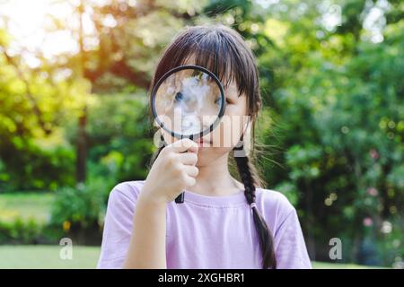 Girl with studying nature looking through magnifying glass, explore nature together with magnifying glass. Analyzing nature with loupe Stock Photo