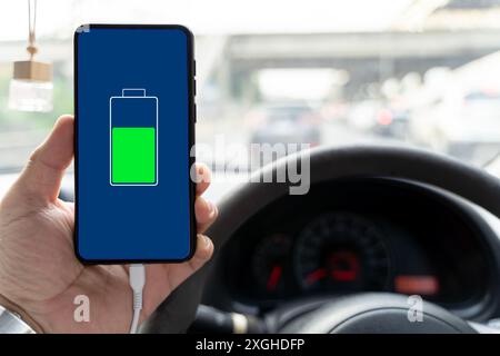 The phone is charging from the car. Mobile phone ,smartphone, cellphone is charged ,charge battery with usb charger in the inside of car. modern black Stock Photo