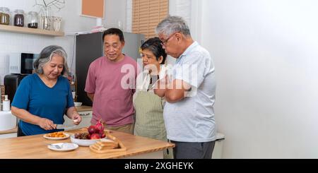 Group of senior friends at home cooking dinner party. Happy senior people group having fun at pic nic barbecue garden diner. Food life style concept w Stock Photo