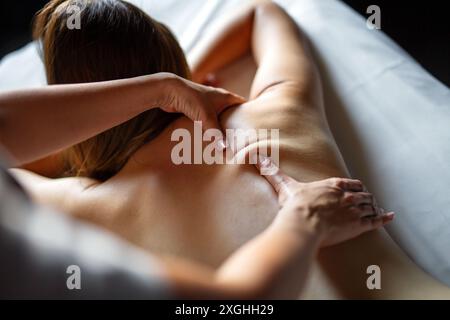 Beautiful happy relaxed woman enjoying professional wellness massage in spa salon Stock Photo