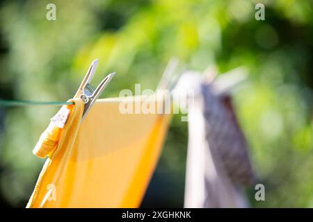 Close up of washing/ laundry hanging outdoors in the summer sunshine drying naturally on a simple washing line, pegged on with clothes pegs. Stock Photo