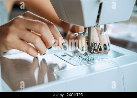 A close-up of the hands of a female seamstress threading a sewing machine. Stock Photo