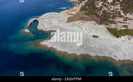 A stunning aerial view of Cane Malu beach in Sardinia, featuring volcanic rock formations and turquoise waters. People are swimming and sunbathing on Stock Photo