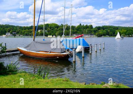 DEU, Deutschland, Nordrhein-Westfalen, Ruhrgebiet, Essen, 08.07.2024: abgedeckte Segelboote am Steg eines Segelclubs am Werdender Ufer auf dem Essener Baldeneysee *** DEU, Germany, North Rhine-Westphalia, Ruhr area, Essen, 08 07 2024 Sailboats covered at the jetty of a sailing club on the Werdender Ufer on Lake Baldeney in Essen Stock Photo